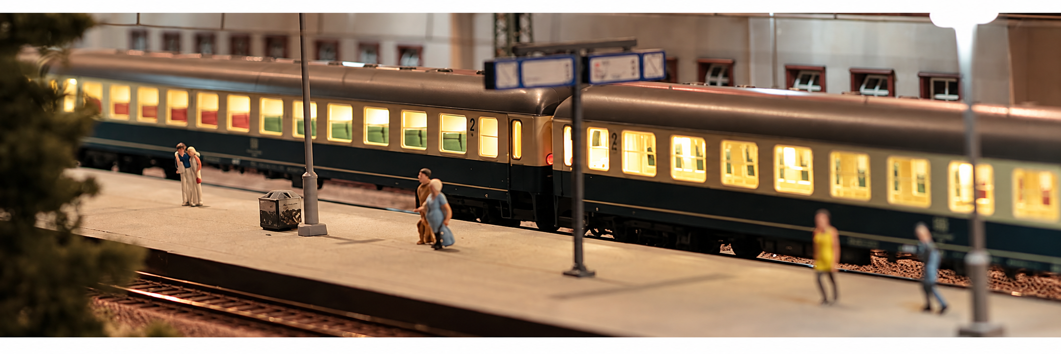Warm beleuchtete Modellbahn-Personenwagen an einem detailreichen Bahnsteig